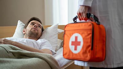 Врач с оранжевым футляром возле кровати пациента